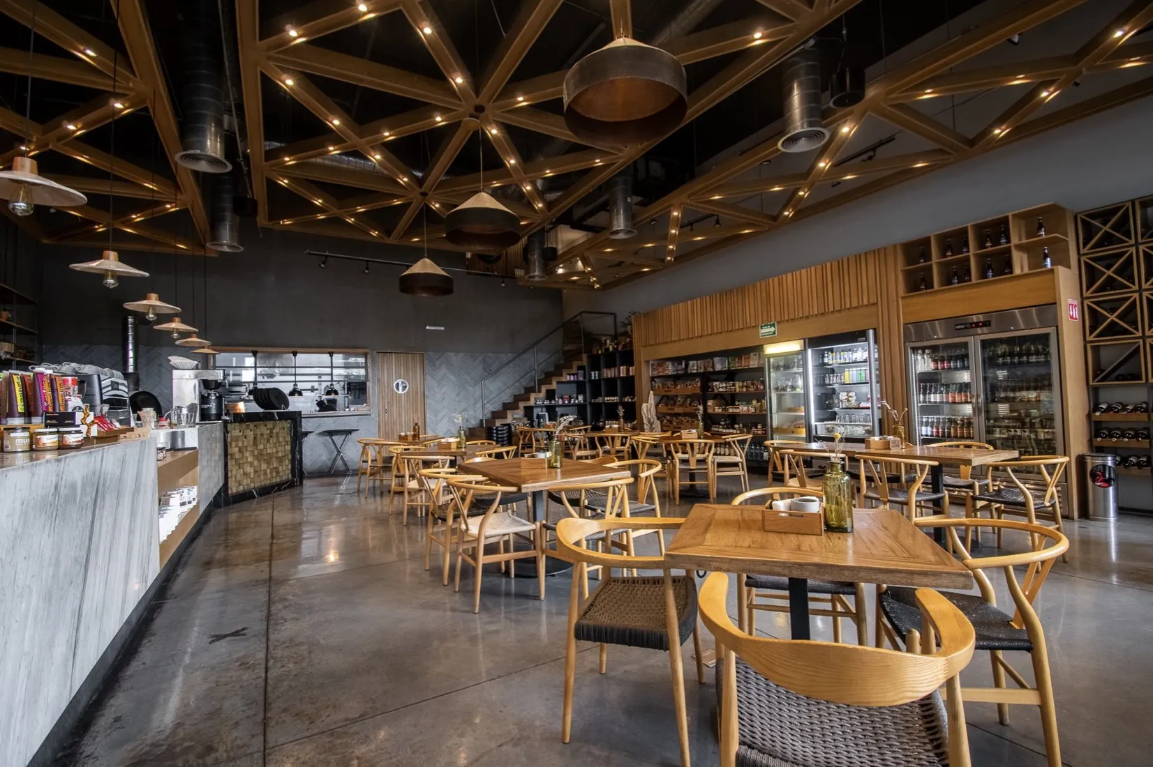 Interior de Cotidiano: mesas y sillas de madera frente a la barra de café